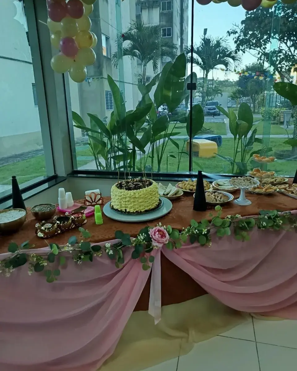 Mesa decorada com bolo, salgados e enfeites florais