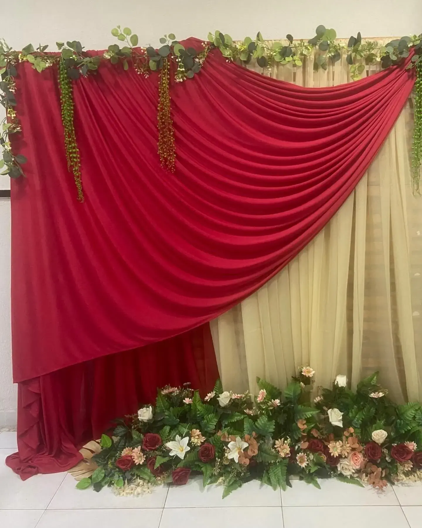 Drapeado vermelho e bege com arranjo de flores no chão